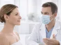 Lekarz w masce rozmawia z pacjentką o zmniejszeniu skrzydełek nosa.