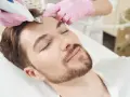 Mężczyzna poddaje się zabiegowi pielęgnacyjnemu twarzy, który jest częścią medycyny stylu życia.