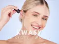 Kobieta aplikuje kroplę serum z kwasami na twarz u kosmetyczki. Zabieg poprawia kondycję skóry.