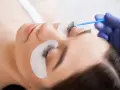 Stylistka aplikuje preparat na rzęsy. To nie jest co to henna, ale zabieg przedłużania rzęs.