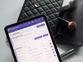 Przykładowa karta klienta salonu kosmetycznego na tablecie, obok czarna kosmetyczka i pędzel do makijażu.