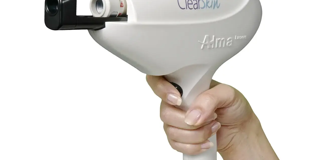 Dłoń trzymająca białe urządzenie laserowe Alma Harmony ClearSkin, gotowe do zabiegu.