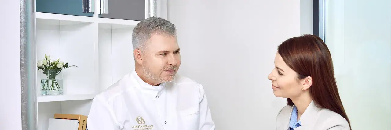 Lekarz specjalista w dziedzinie dermatologii i wenerologii rozmawia z pacjentką w gabinecie.